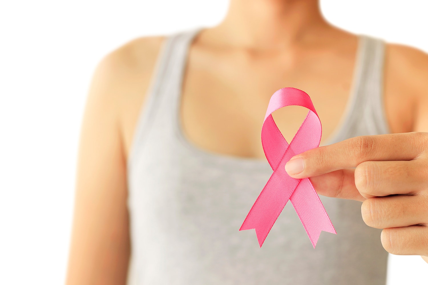 Close-up on a woman holding out a pink ribbon arranged into the symbol for breast cancer awareness