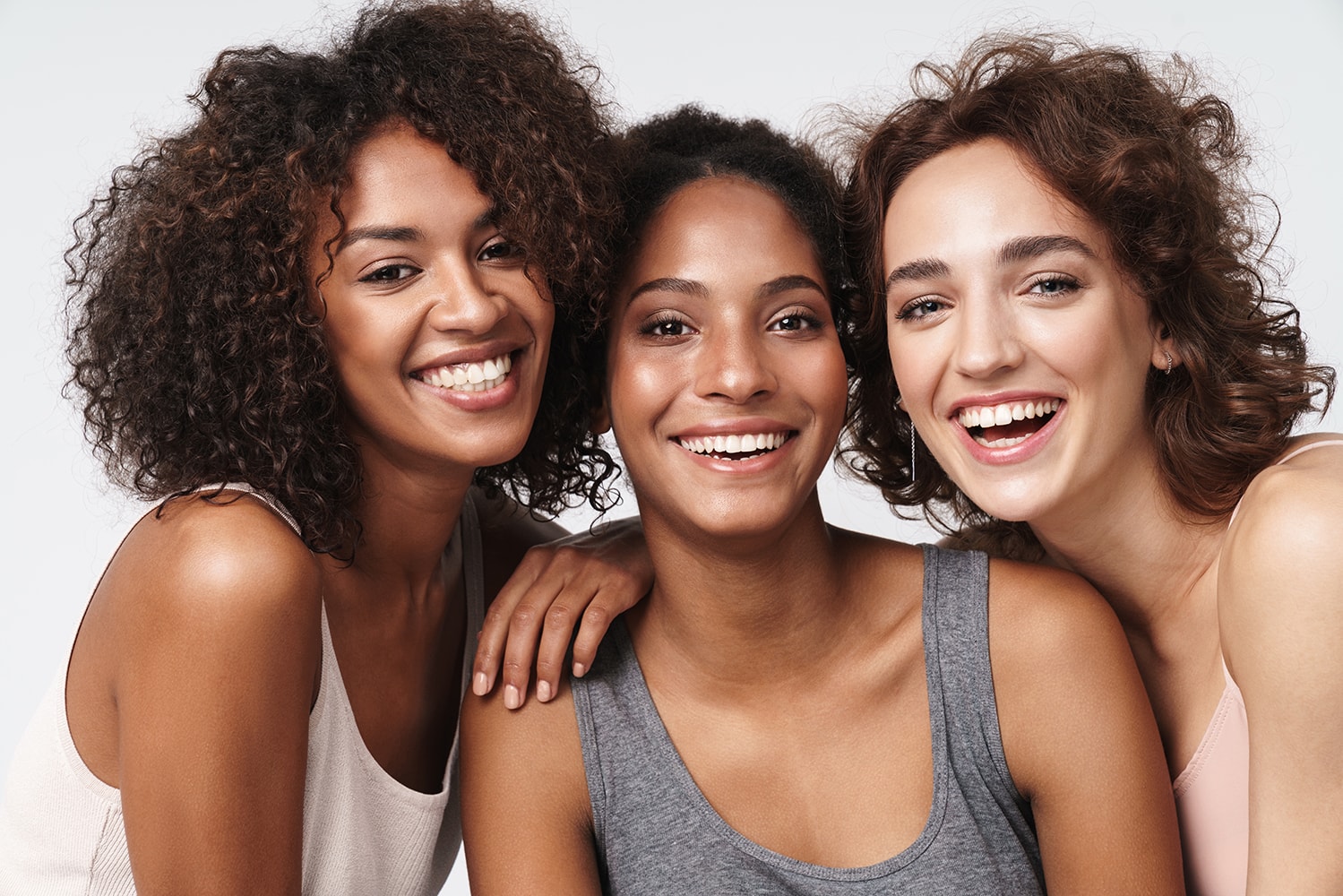 Three women leaning together and smiling at the camera